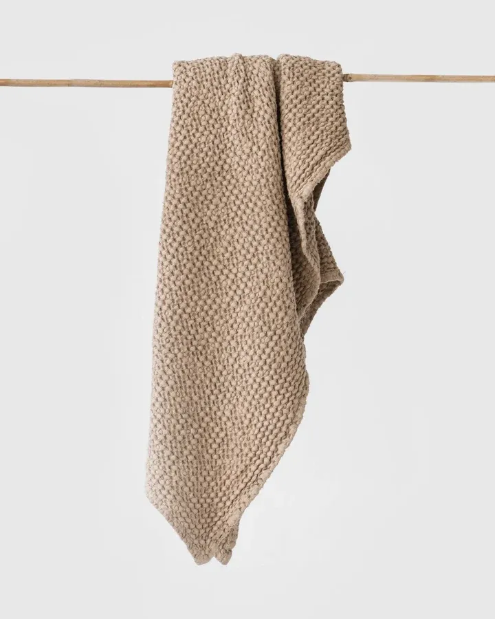 Beige wafelhanddoek van MagicLinen, over een houten stok gehangen