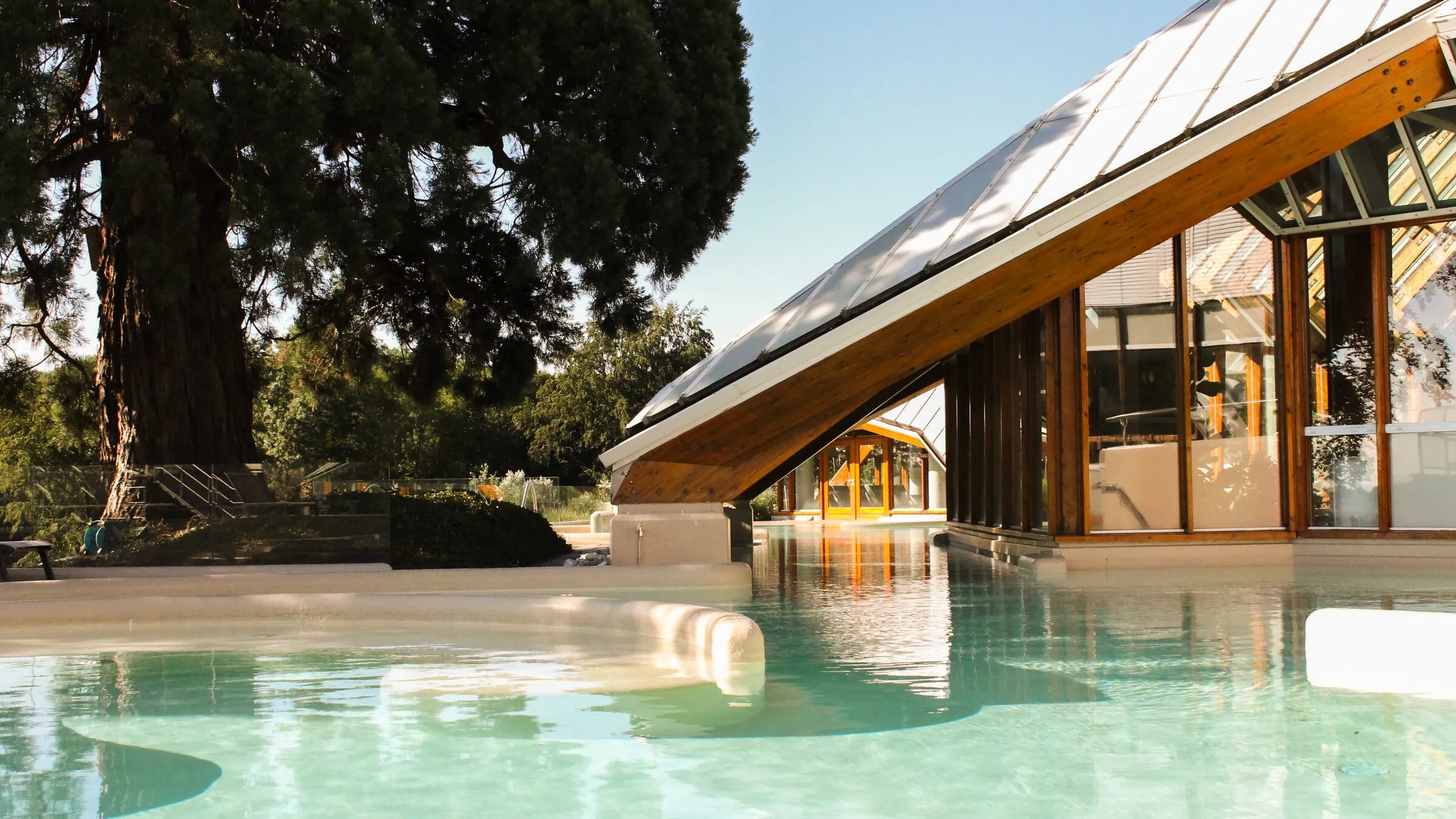Het thermale buitenbad van Thermae 2000 met de glazen piramide van het resort en de oude sequoia