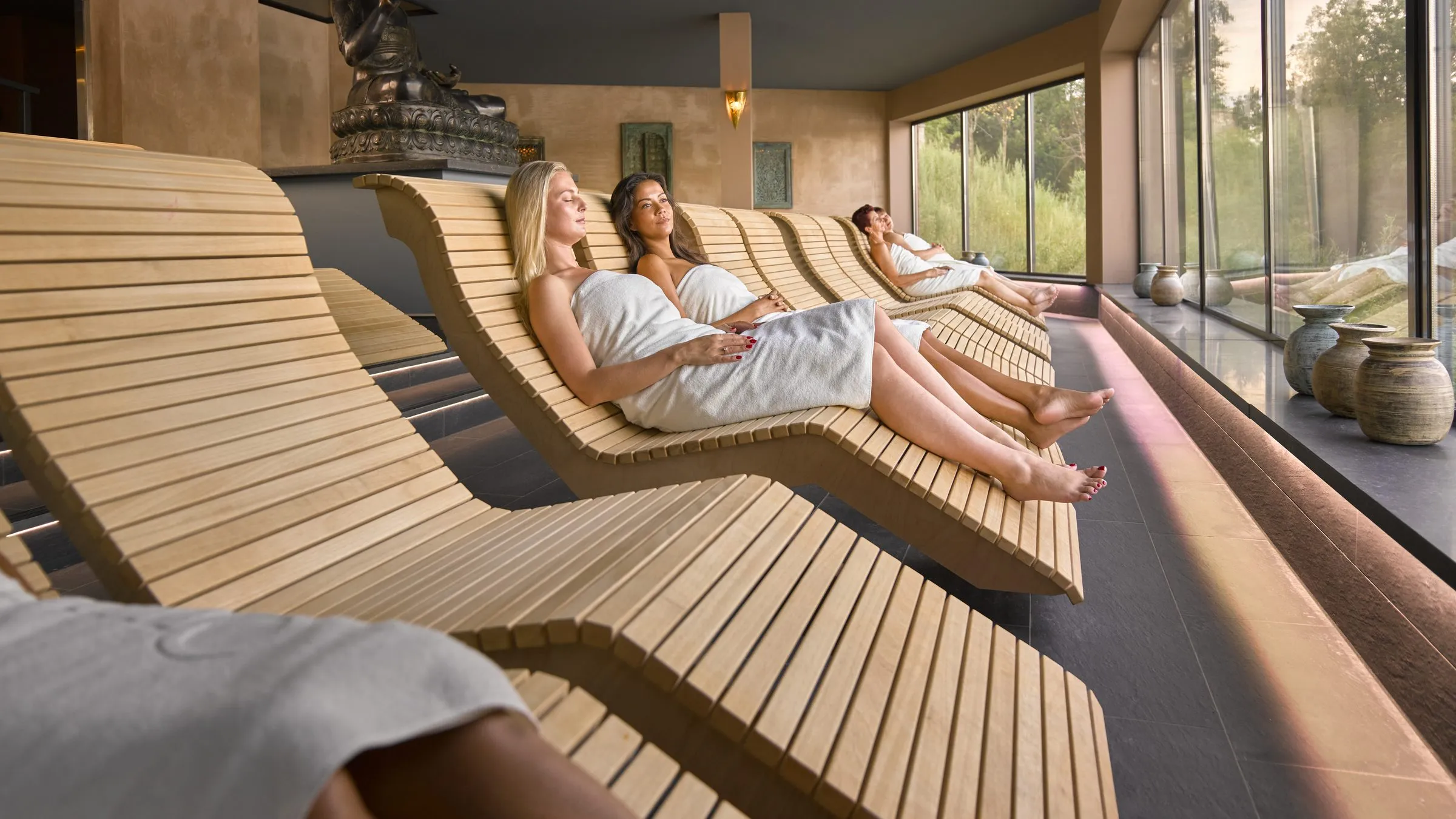 De meditatiesauna van Thermen Berendonck met golvende houten ligbanken en uitzicht op de tuin
