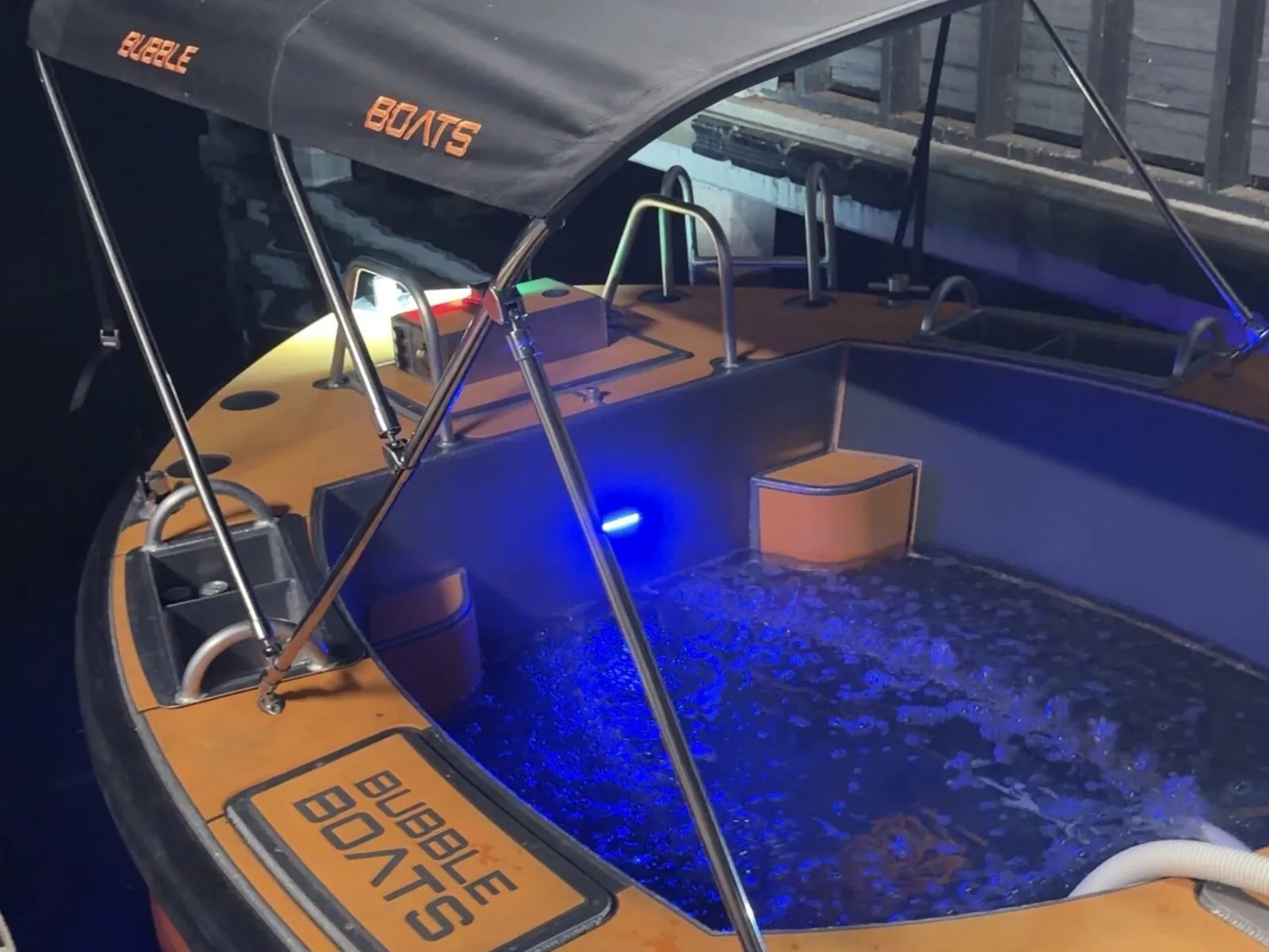 Varende jacuzzi van Bubble Boats aan de steiger in Loosdrecht in het donker, met het dak erop en blauw verlicht water